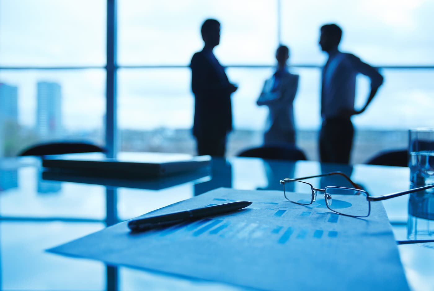 Siluetas de profesionales frente a ventanales en oficina corporativa, representando el sector empresarial mexicano
