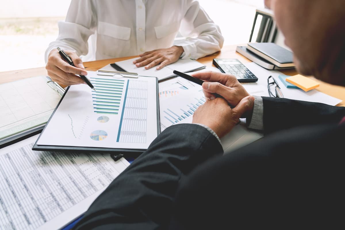 Persona revisando documentos financieros y gráficos de comercio internacional